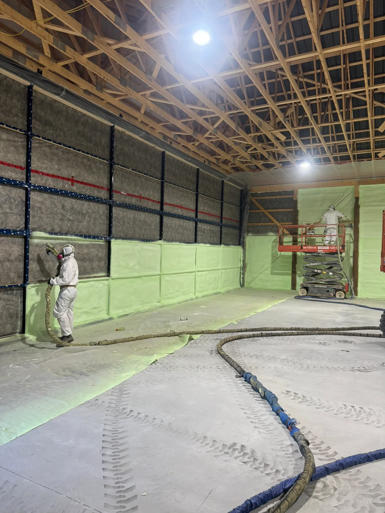 Installer applying closed-cell spray foam to a wall to code-specified thickness